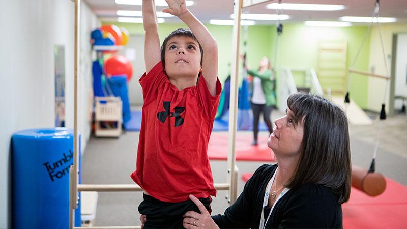 SPH pediatric therapist and patient on monkey bars