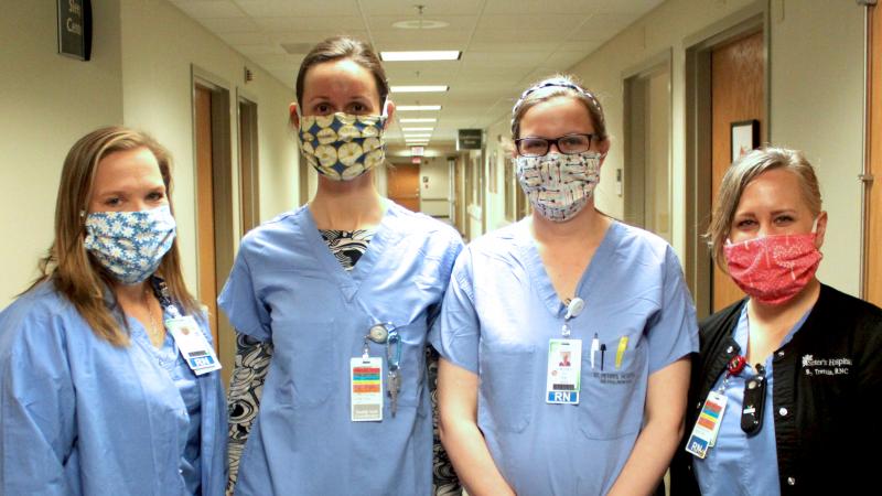 Caregivers pose wearing cloth masks donated by community members